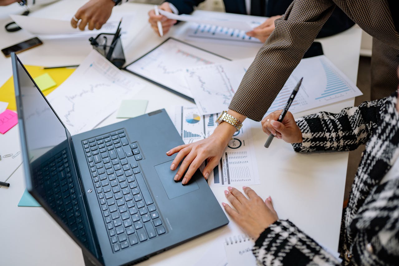Business team analyzing data and charts during a meeting with a laptop on the table.
